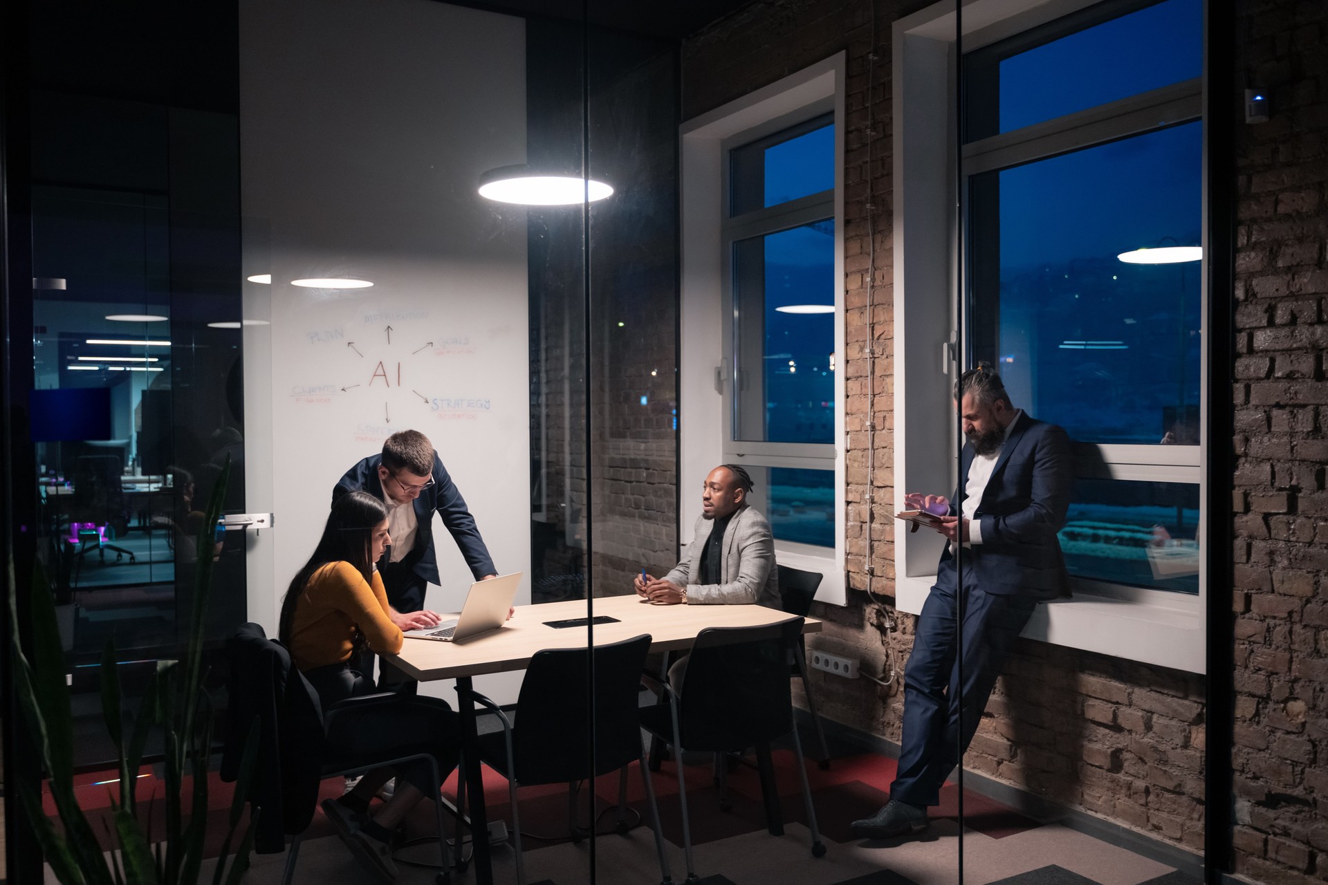 Diverse business team discussing artificial intelligence strategy in a modern office during late hours. Concept of teamwork, innovation, and technology-driven decision-making
